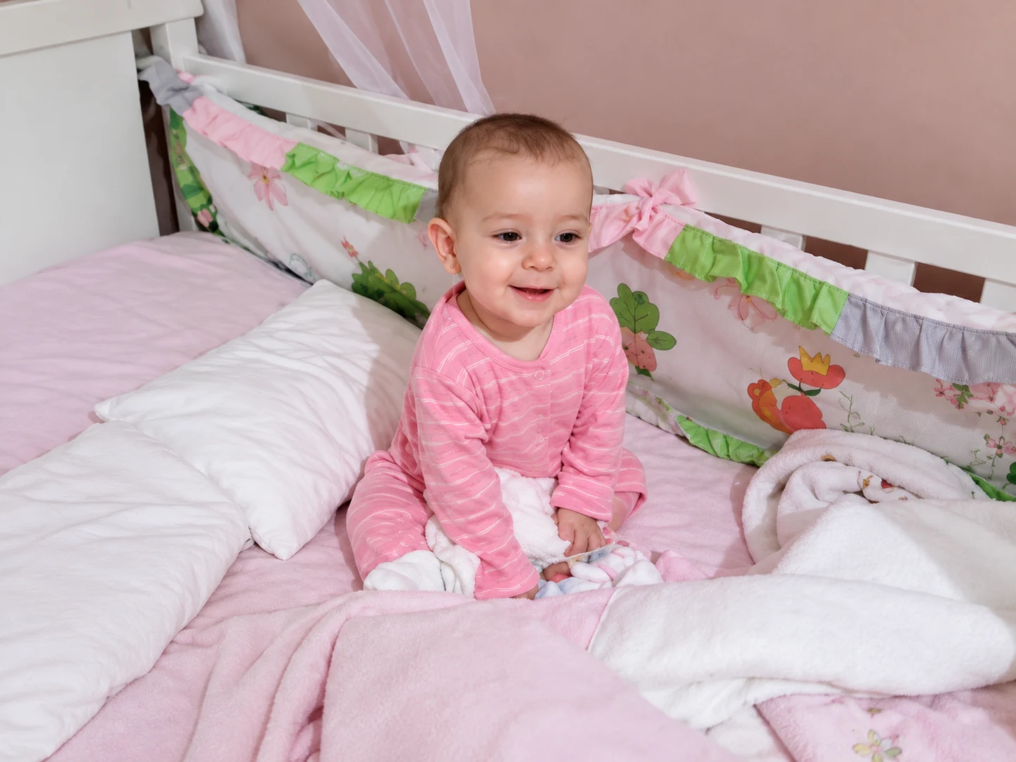 Lara ainda bebê, sorrindo sentada em seu berço