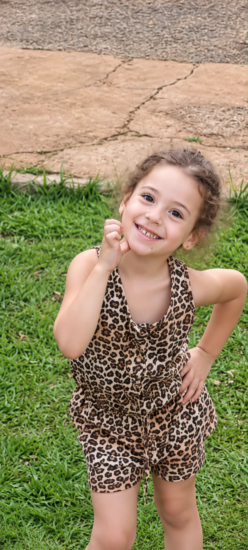 Lara criança, sorrindo no gramado com roupa de oncinha